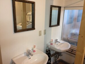 A bathroom with two sinks, a mirror, and a window with a mesh screen. - Guest House YASUBE - Hostel (Sapporo)