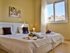 A hotel room with a bed, a nightstand, a lamp, and a window with a view of buildings.
