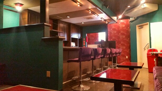A bar area with high stools, a counter, and a red table. - Dormitory in Kowloon - Hostel (Naoshima)