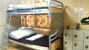 A bunk bed with a ladder, a mattress, and pillows. There is a storage unit with labeled compartments. - Dormitory in Kowloon - Hostel (Naoshima)