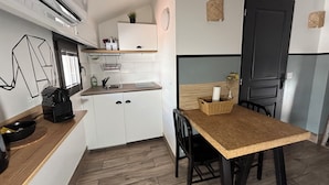 A compact kitchen with white cabinets, a wooden countertop, a sink, and a dining area with a table and chairs.