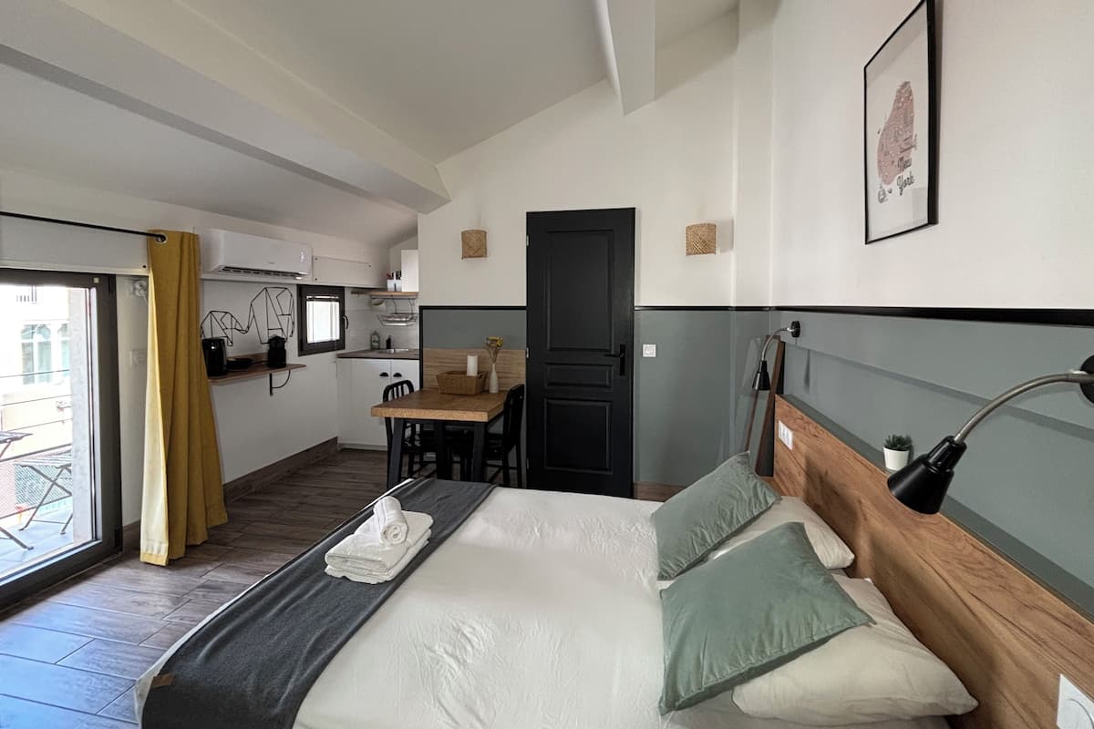 A compact hotel room with a bed, a desk, and a kitchenette.