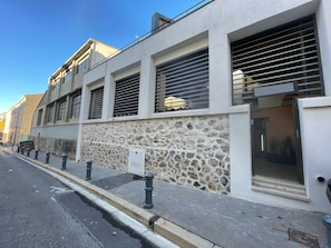 A modern building with a stone facade, large windows with horizontal blinds, and a visible door. - Casahotel (Aix-en-Provence)