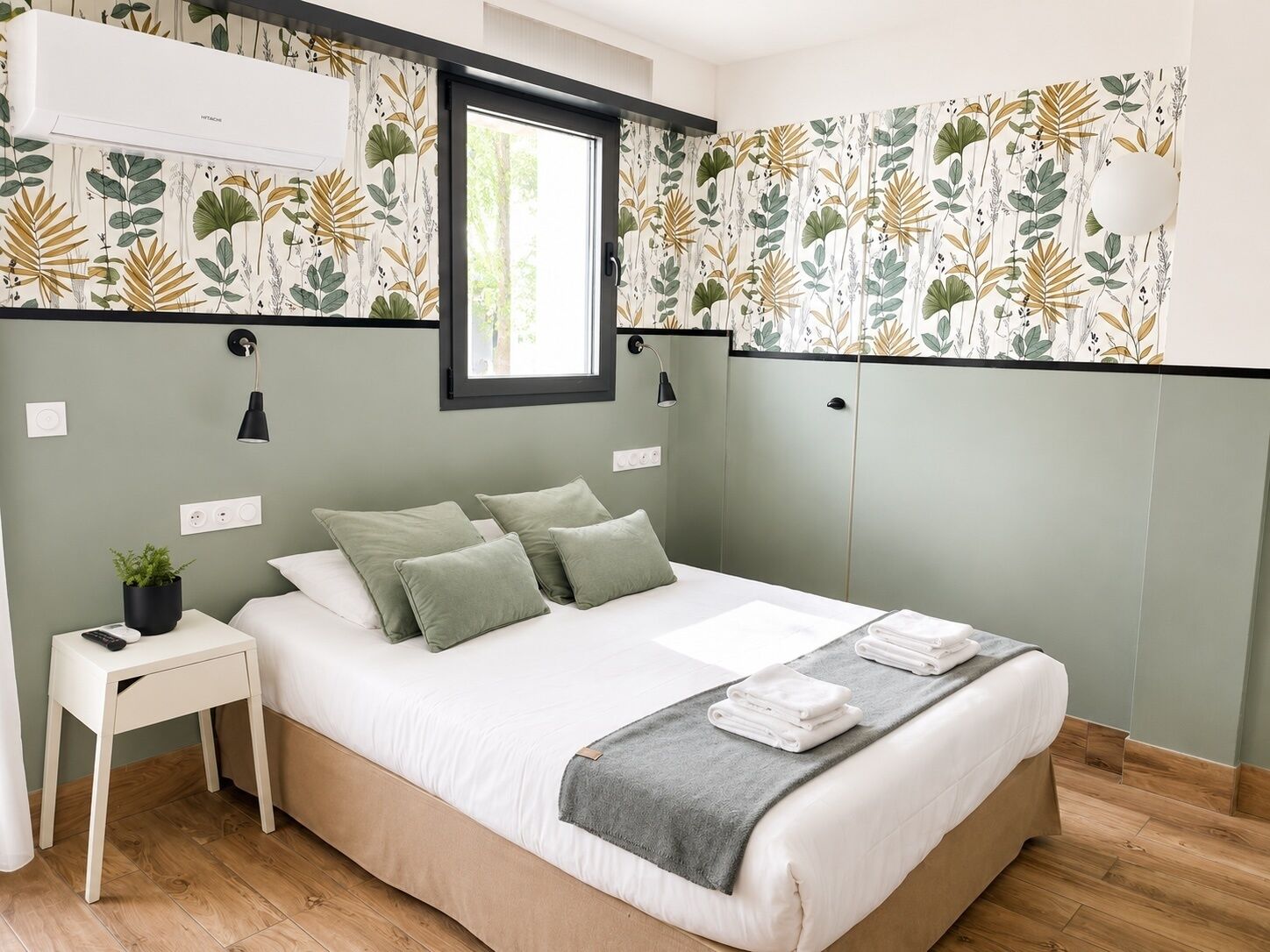 Ein Schlafzimmer mit Bett, Nachttisch, Lampe und Fenster.