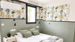 A bedroom with a bed, bedside table, lamp, and a window.