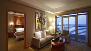Une chambre d’hôtel avec un lit, un canapé, une table basse et une grande fenêtre donnant sur la mer.