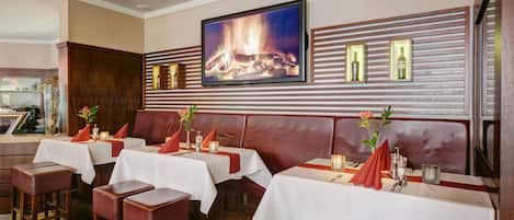 Un restaurante con cabinas, mesas y chimenea.