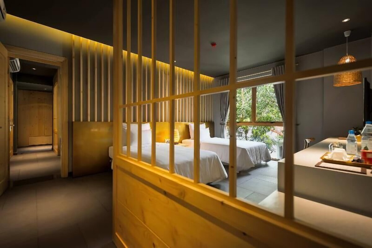 A hotel room with a bed, bedside table, and a view of the outdoors.