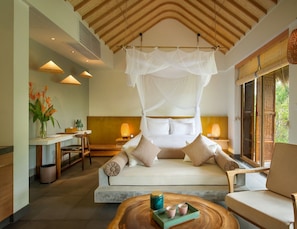 A modern bedroom with a canopy bed, a sitting area with a sofa and chairs, a dining table, and a view of greenery outside.