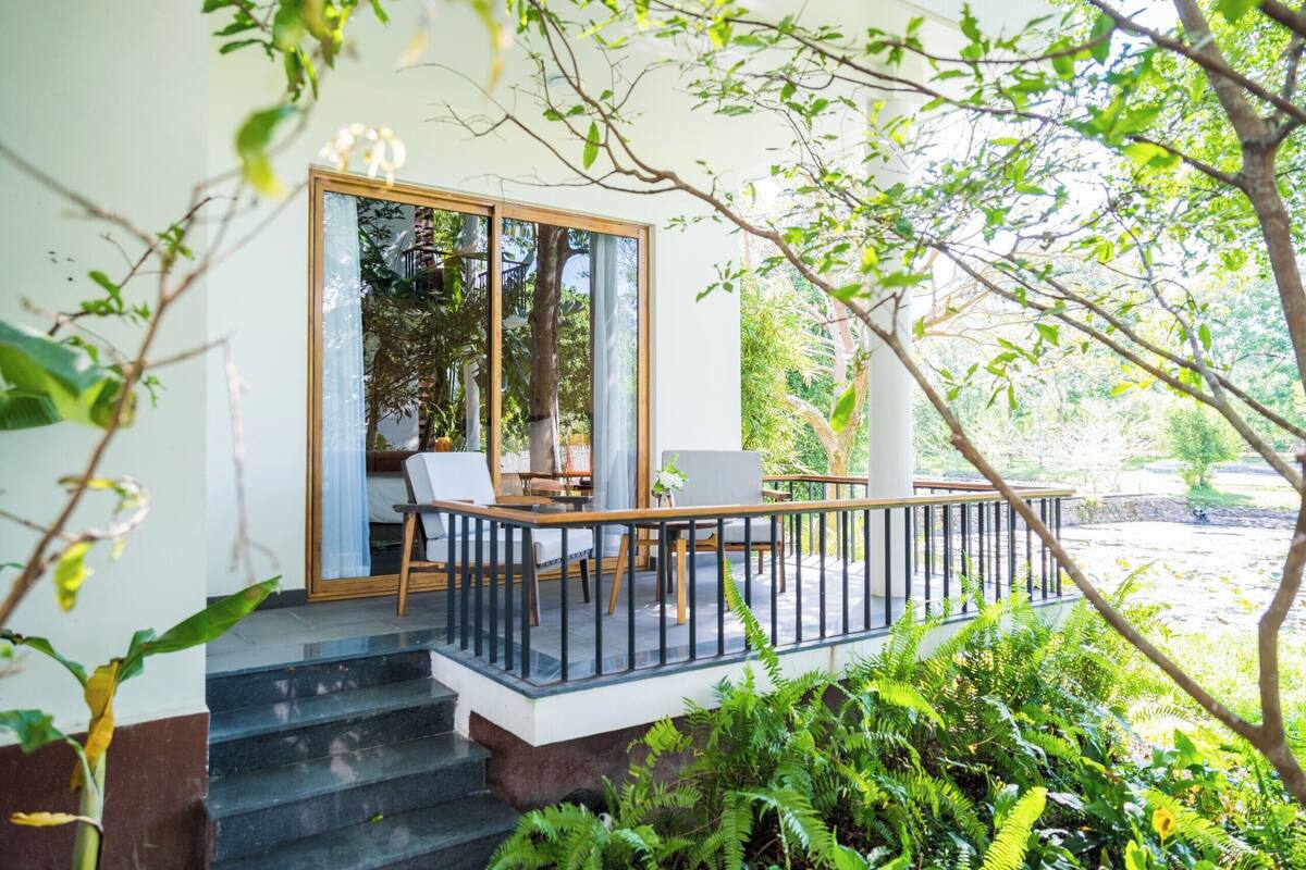 Een moderne buitenruimte met een glazen balustrade, een houten terras en een trap naar een glazen deur.