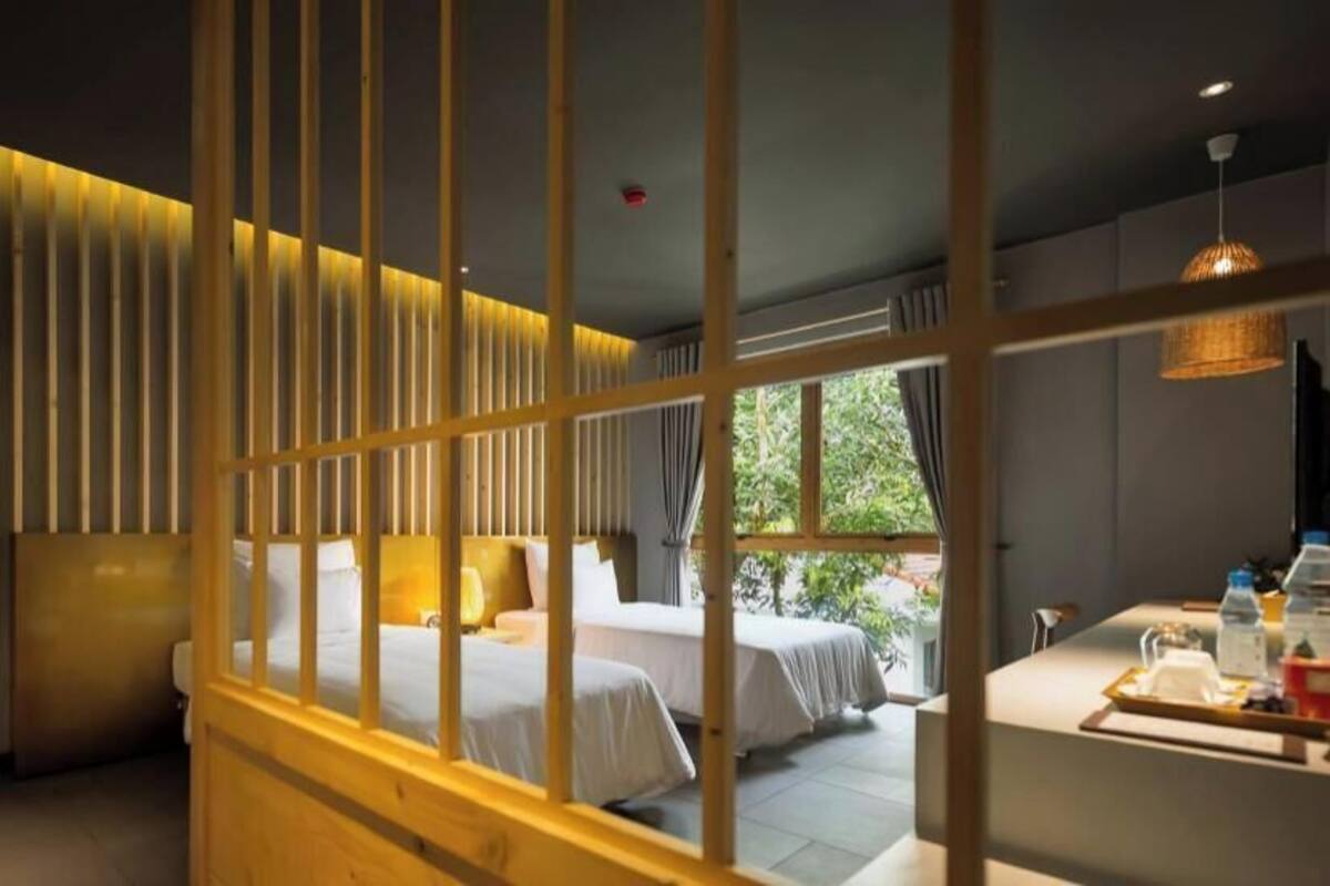 Een hotelkamer met een bed, een bureau met stoel, een raam en een deur.
