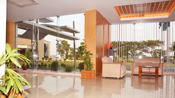Um hall moderno com divisória de vidro, colunas de madeira, um sofá e uma mesa de centro.