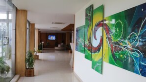 Um hall moderno com arte abstrata nas paredes, uma televisão ao fundo e plantas em vasos.
