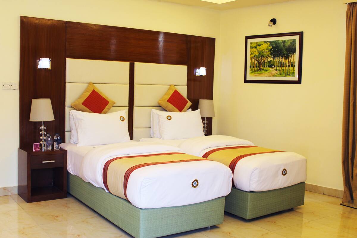 A double bed with two pillows, a nightstand with a lamp, and a framed picture on the wall.