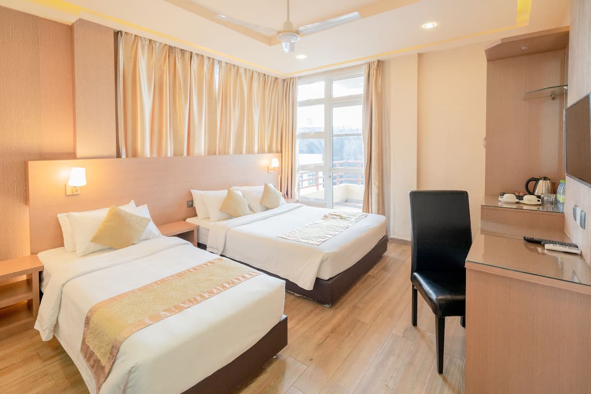 A hotel room with two beds, a desk, and a chair.