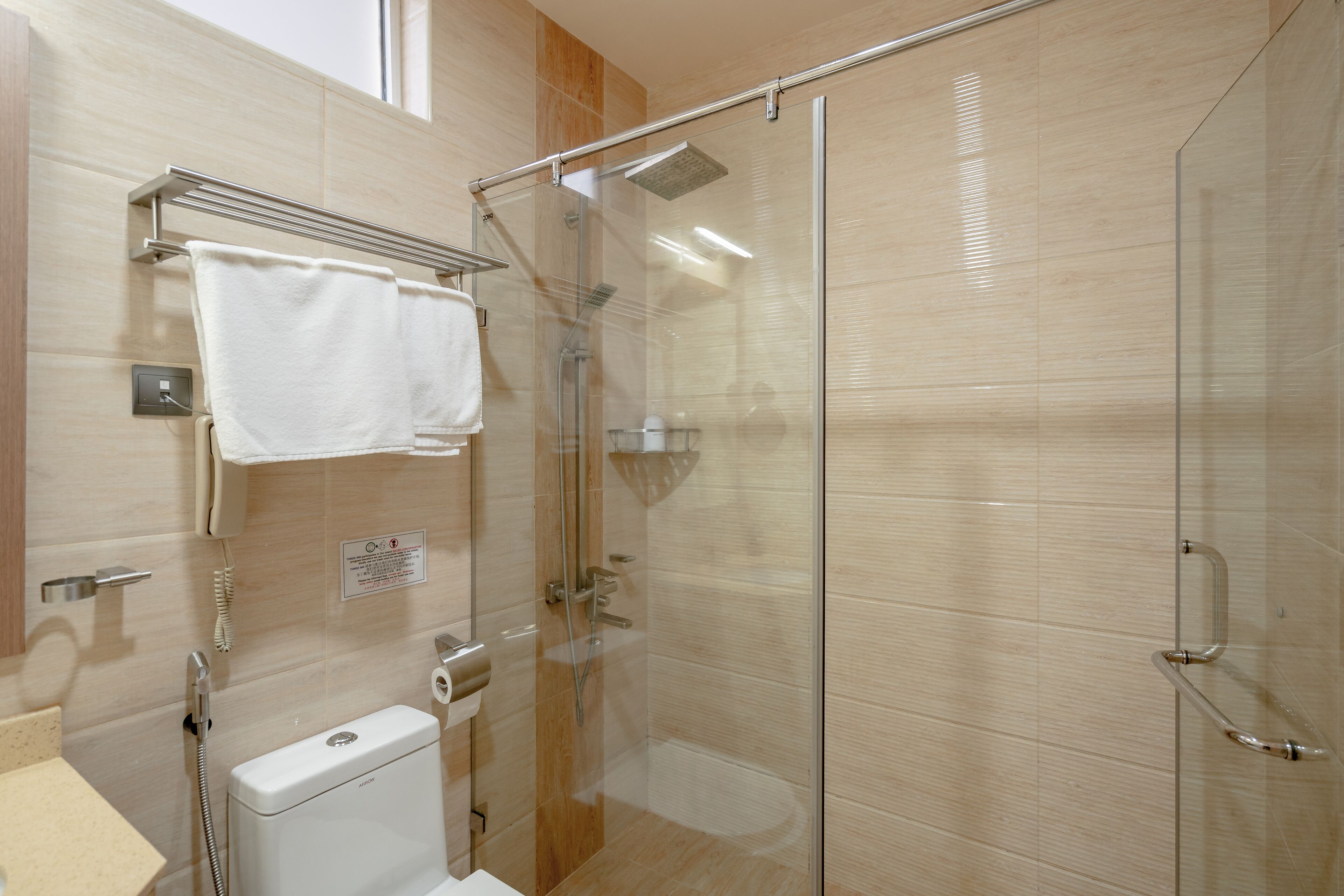 Un baño moderno con ducha de vidrio, inodoro y barra para toallas.