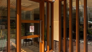 A modern building entrance with large glass doors, a wooden ceiling with slats, and a tiled floor. - Three Inn (Hulhumalé)