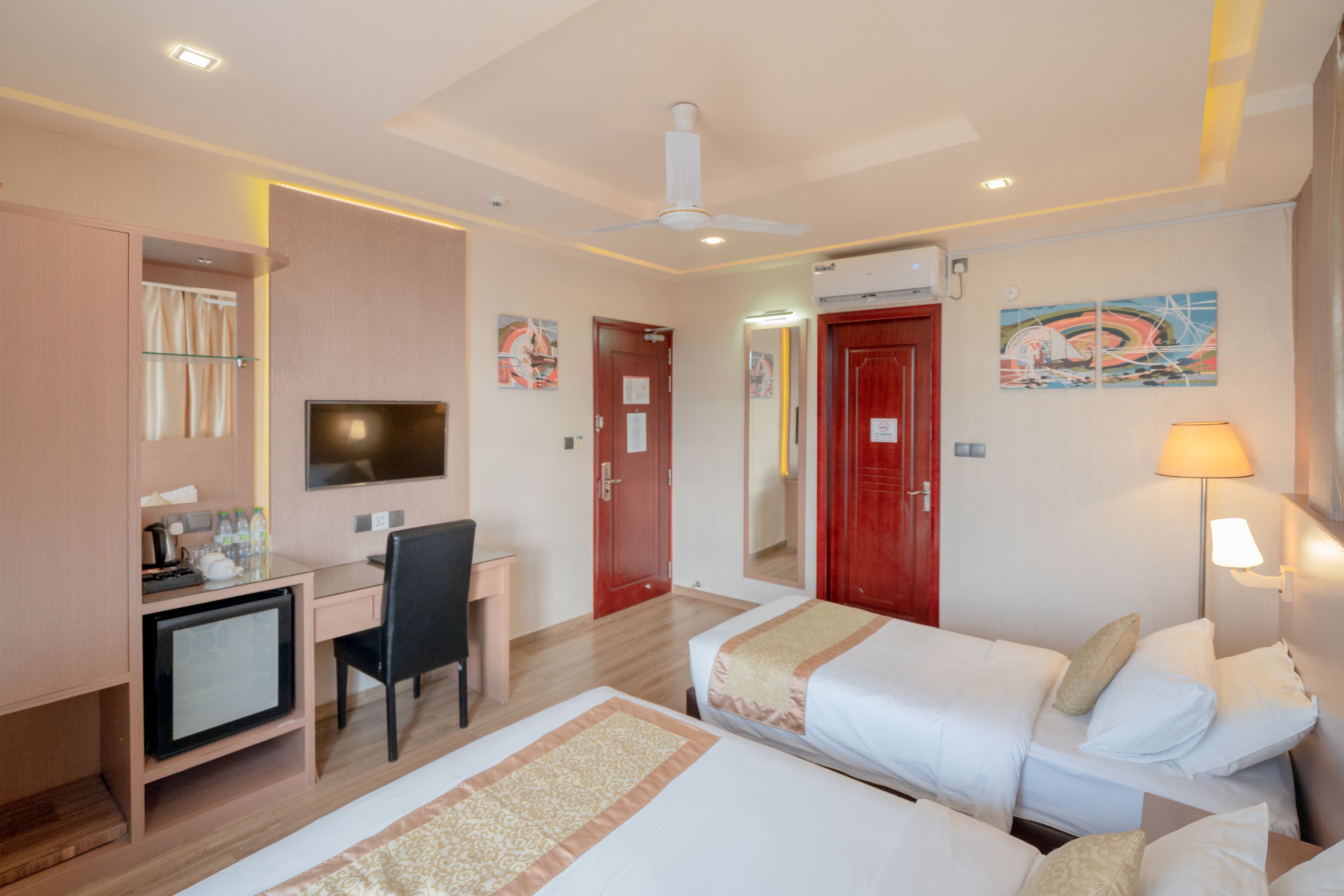Une chambre d’hôtel avec un lit, un bureau, une chaise, une télévision et une porte rouge.