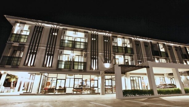 A modern hotel with a covered entrance, large windows, and a parking area. - Pentahug Hotel (Ubon Ratchathani)