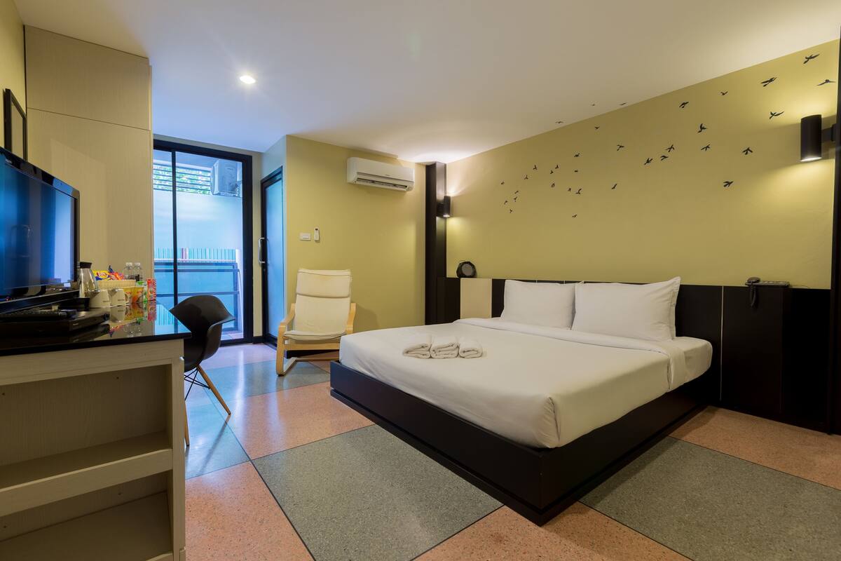 Quarto de hotel com uma cama, uma mesa, uma cadeira e uma televisão.