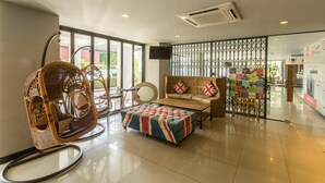 A modern hotel lobby with a wicker chair, a cushioned bench, and a wooden sofa. - Pentahug Hotel (Ubon Ratchathani)