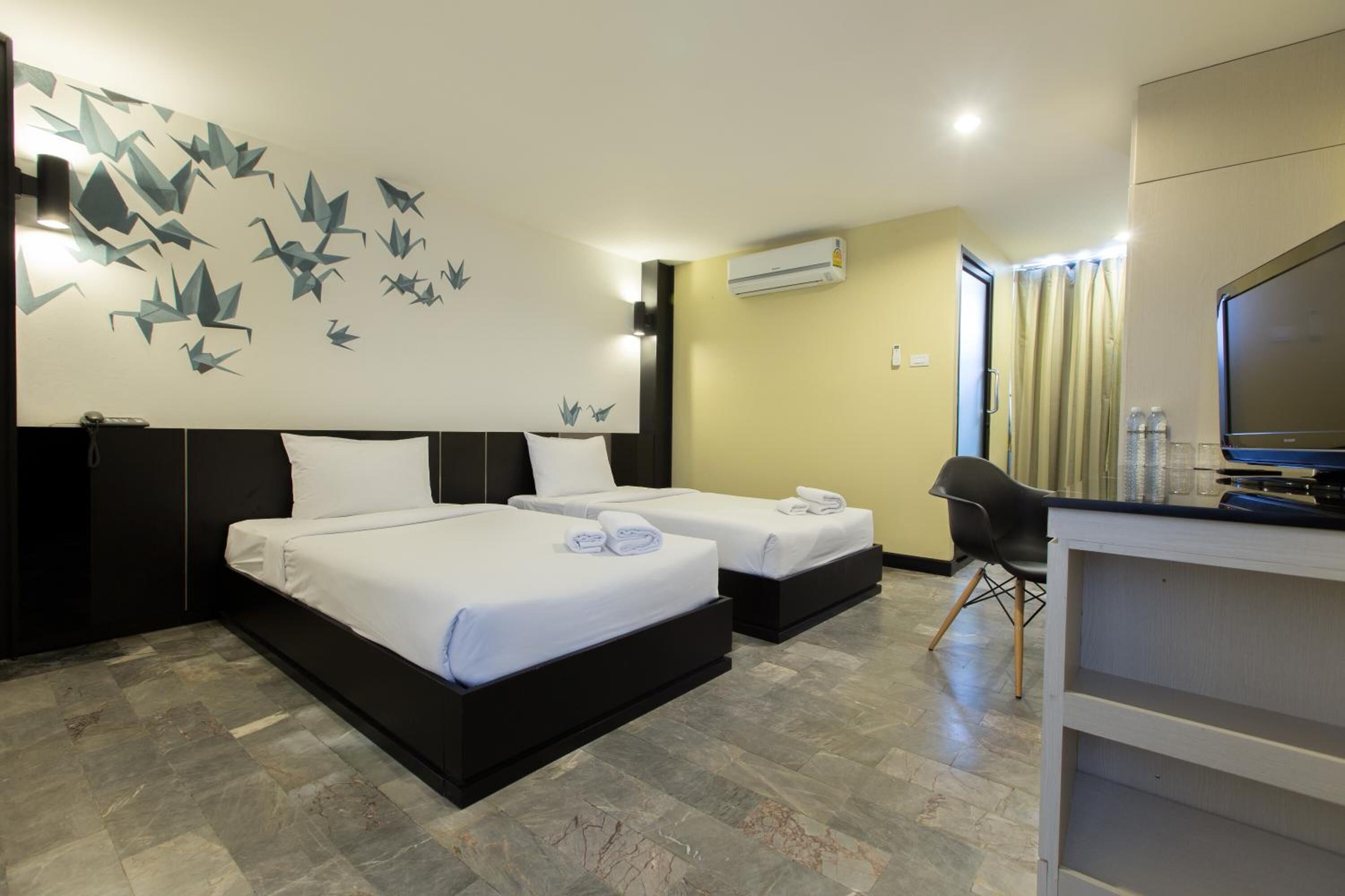 A hotel room with two beds, a desk, and a television.