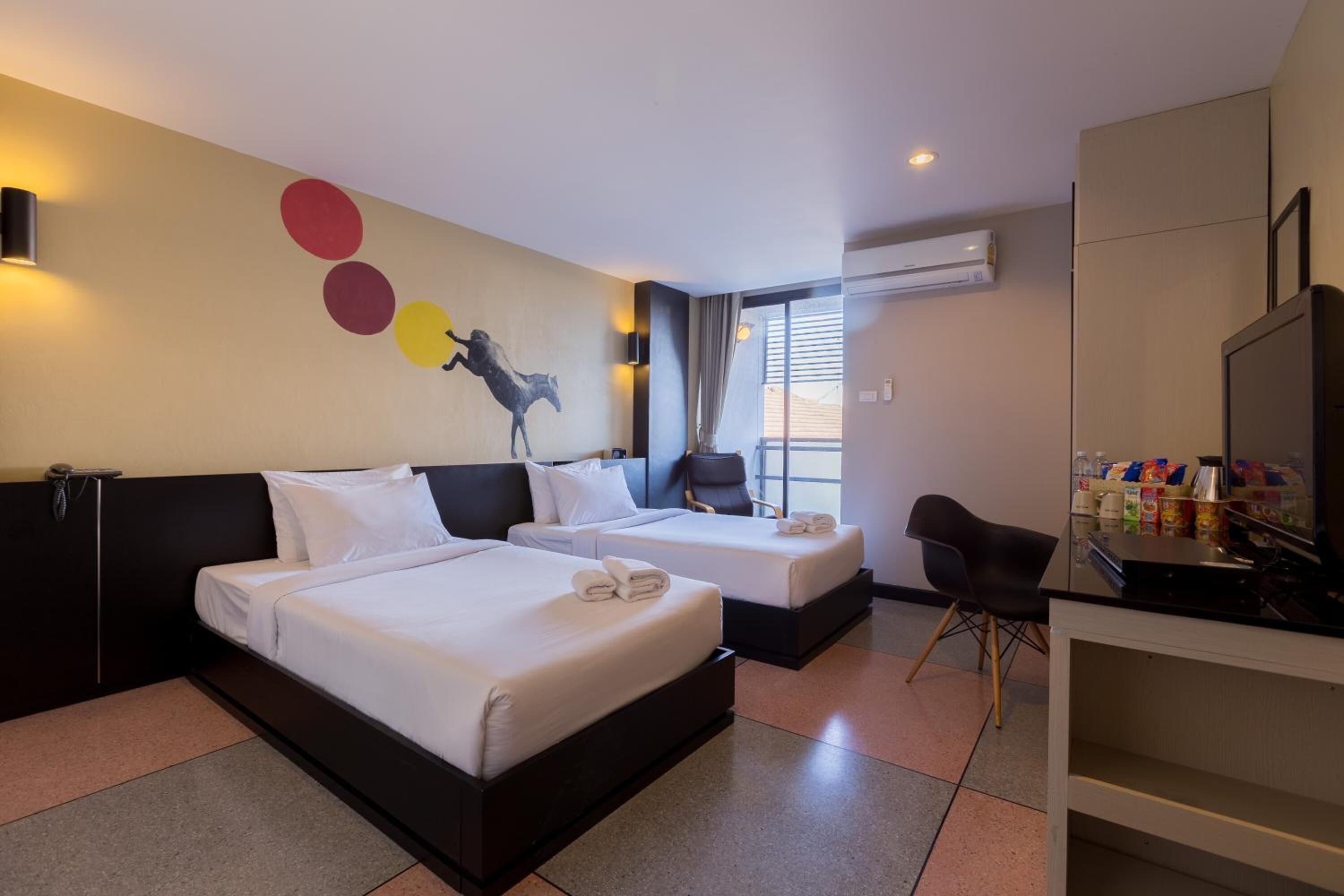 Una habitación de hotel con dos camas, un escritorio, una silla y un televisor.