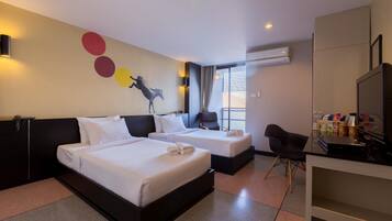 A hotel room with two beds, a desk, a chair, and a TV.