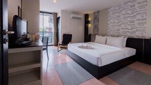 A hotel room with a bed, a desk with a television, a chair, and a wall with city names. - Pentahug Hotel (Ubon Ratchathani)