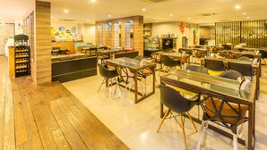 A modern restaurant with wooden flooring, glass tables, and black chairs. - Pentahug Hotel (Ubon Ratchathani)