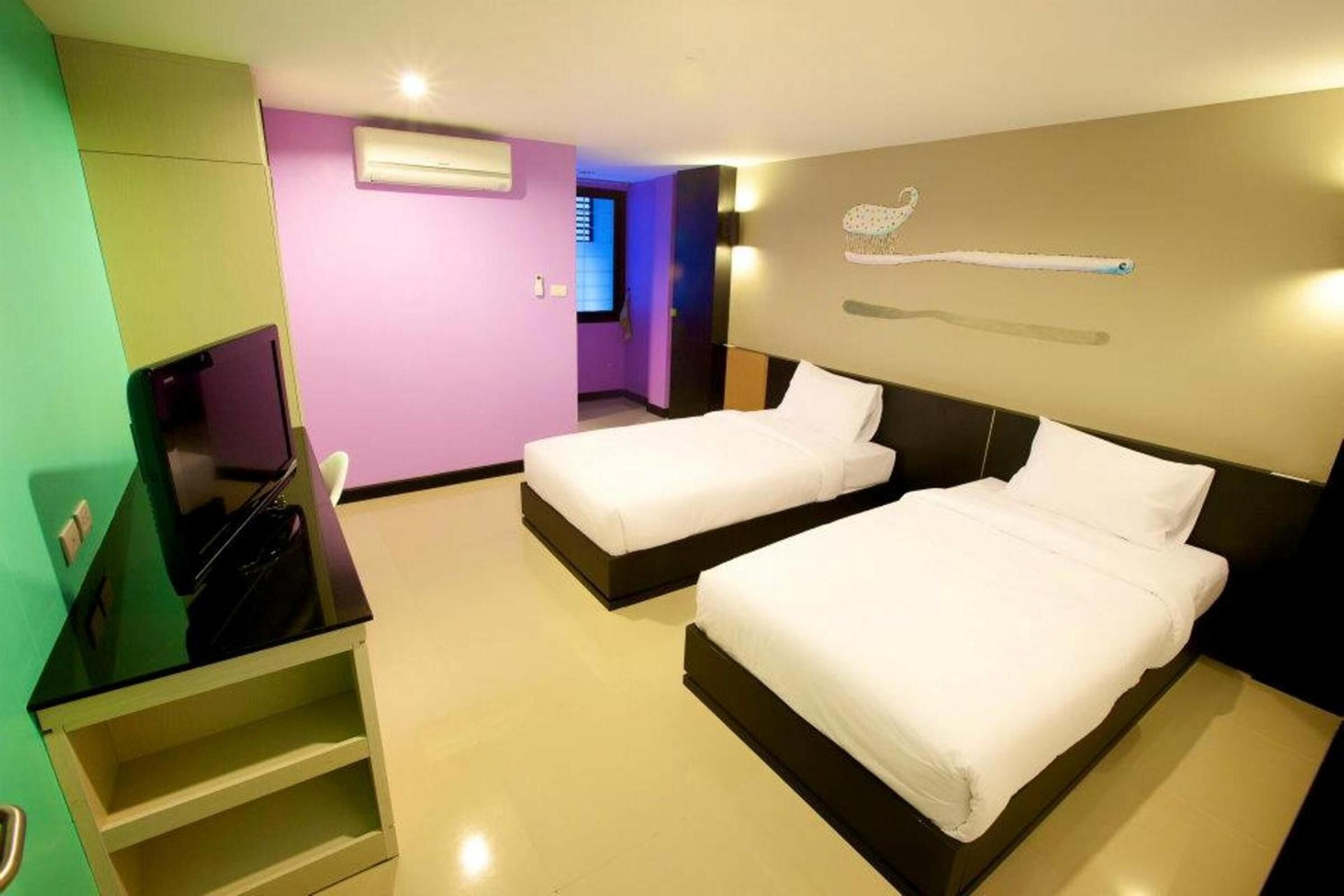 A hotel room with two beds, a TV, a desk, and a bathroom.