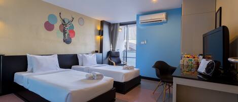 Habitación de hotel con dos camas, televisor, escritorio y ventana con cortinas.