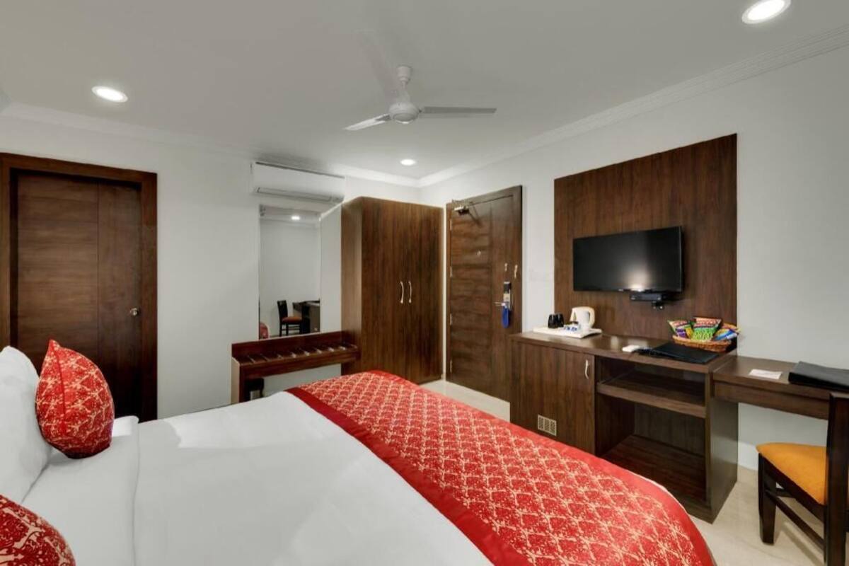 A hotel room with a bed, a desk, a television, and a wardrobe.