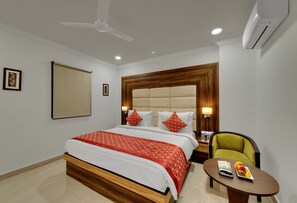 Habitación de hotel con cama, una silla, una mesa con una bandeja de fruta, ventilador de techo y aire acondicionado.