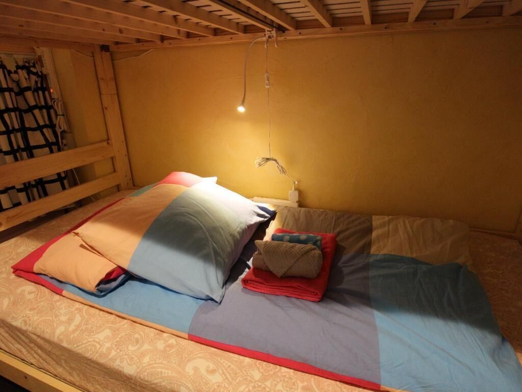 A bunk bed with a single bed on top. There is a hanging light fixture above the bed.