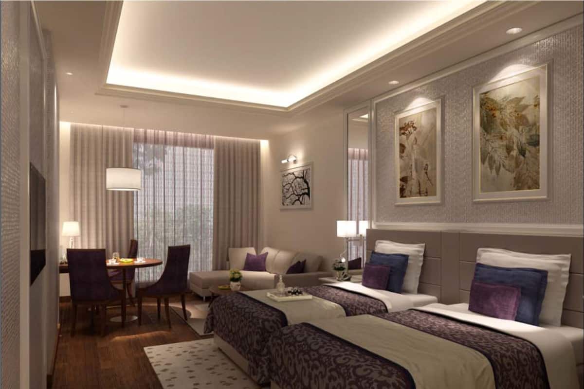 A hotel room with two beds, a dining area, and a large window with curtains.