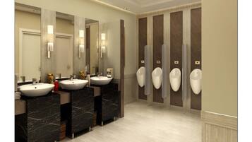 Des toilettes publiques équipées de trois lavabos, de miroirs et d’urinoirs fixés au mur.