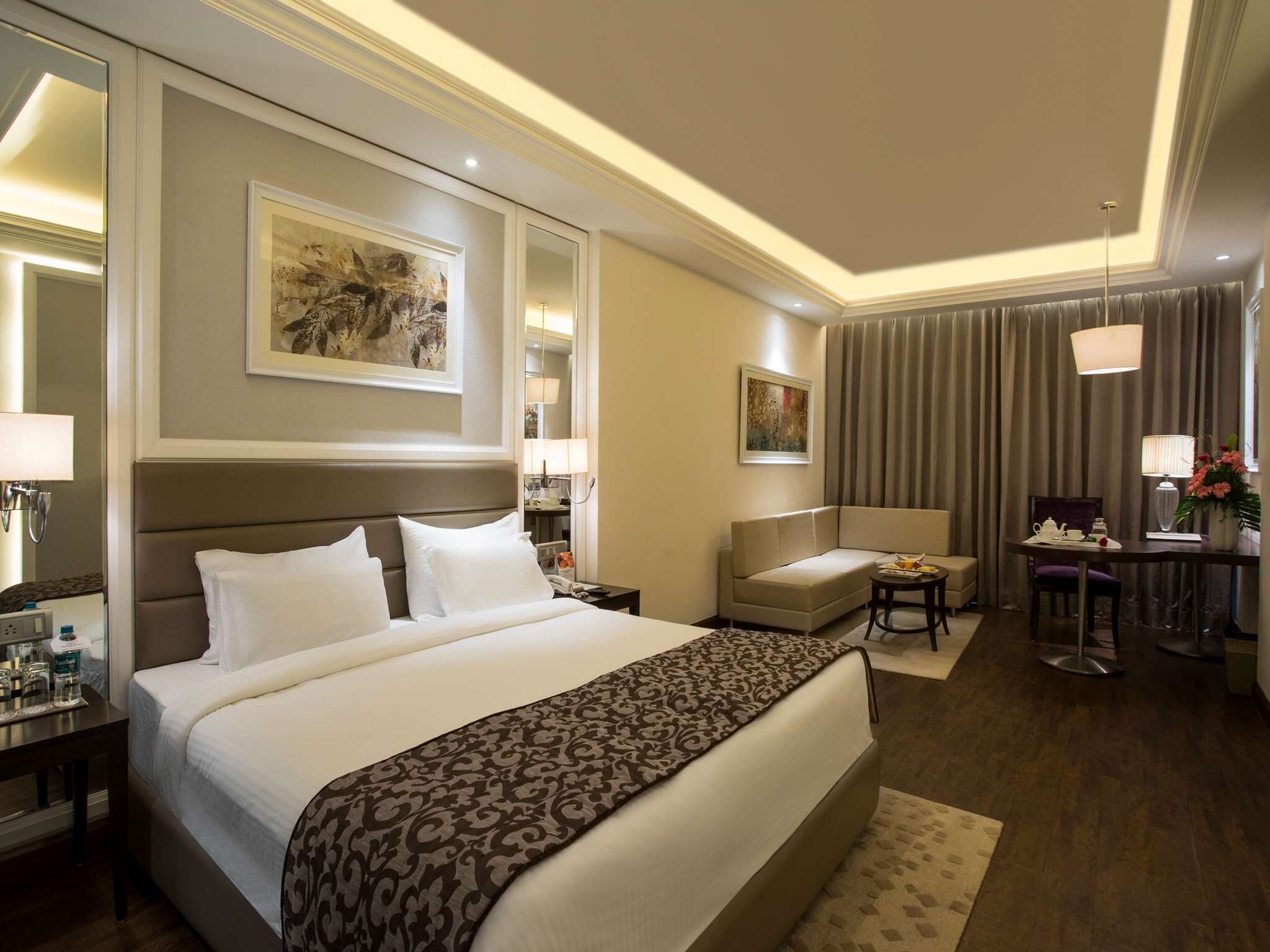 Een hotelkamer met een groot bed, een bank, een kleine tafel en een bureau met een stoel.