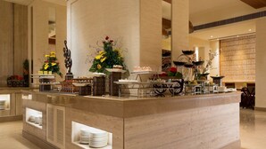 A hotel reception area with a marble counter, decorative plants, and a variety of food and drink items.