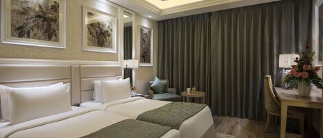 A hotel room with two beds, a desk, a chair, and artwork on the walls.