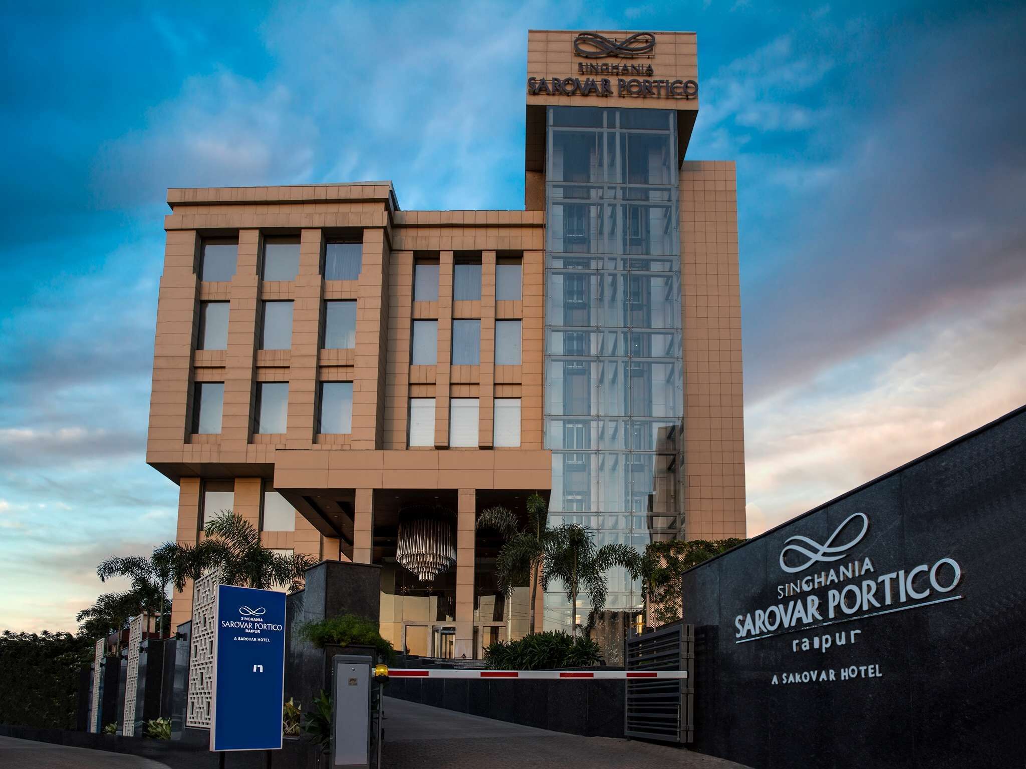 A modern hotel building with a prominent sign for Singhania Sarovar Portico.