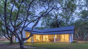 A modern house with a large glass door and windows, surrounded by trees. - Cashew Cashew Villa (Phu Quoc)