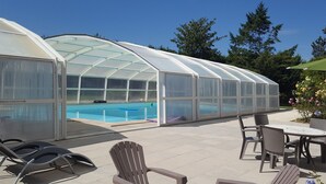 Une serre abritant une piscine, un espace salon extérieur et un patio.