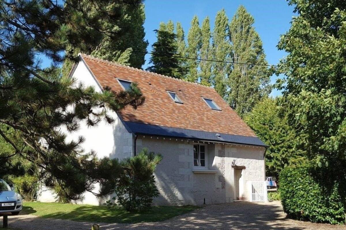 A single-story house with a sloped roof, a small front porch, and a gravel driveway.