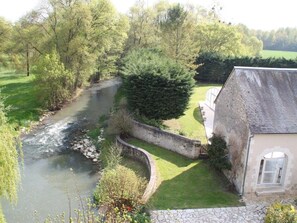 A riverside property with a stone house, a grassy lawn, and a stone wall. - Le Moulin de Bacchus (Chançay)