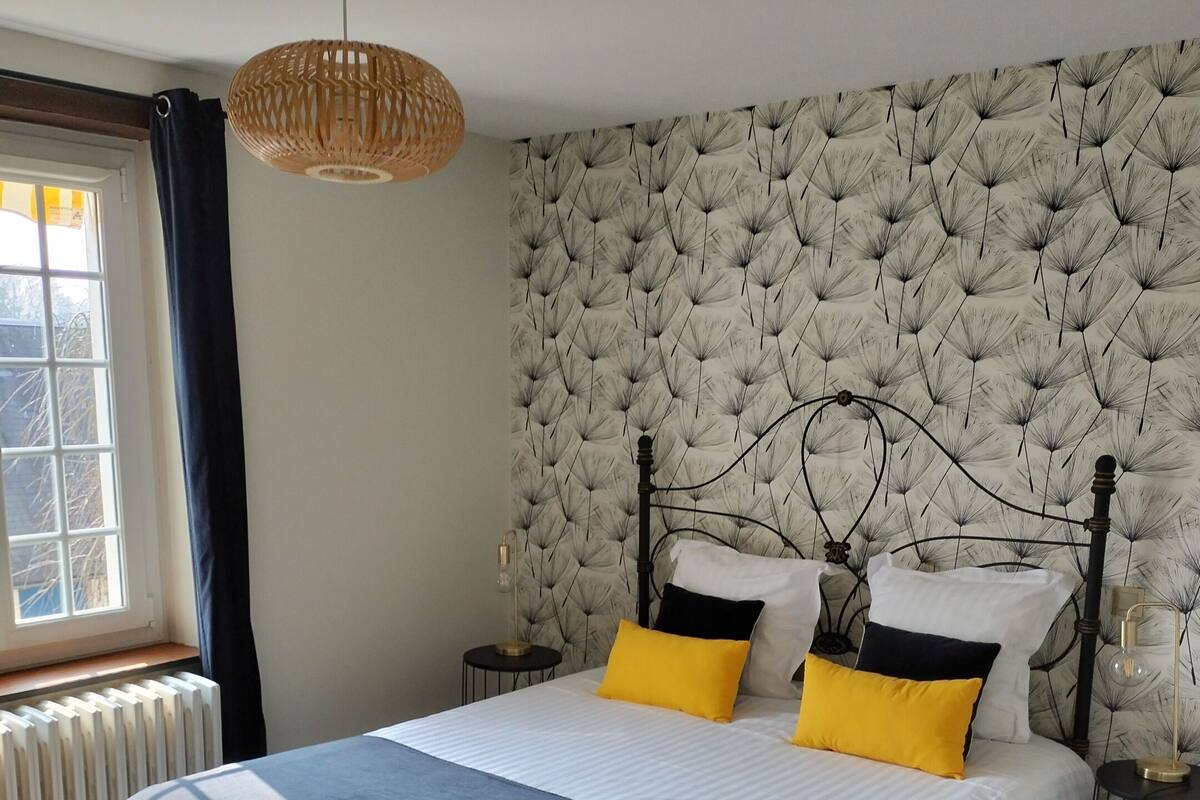 A neatly made bed with a white and black bedspread, two yellow pillows, and a headboard with a textured pattern.