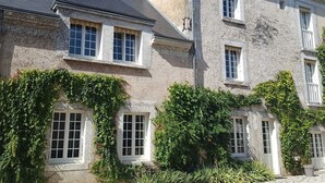 Un bâtiment en pierre doté de nombreuses fenêtres et d’une entrée abritée.