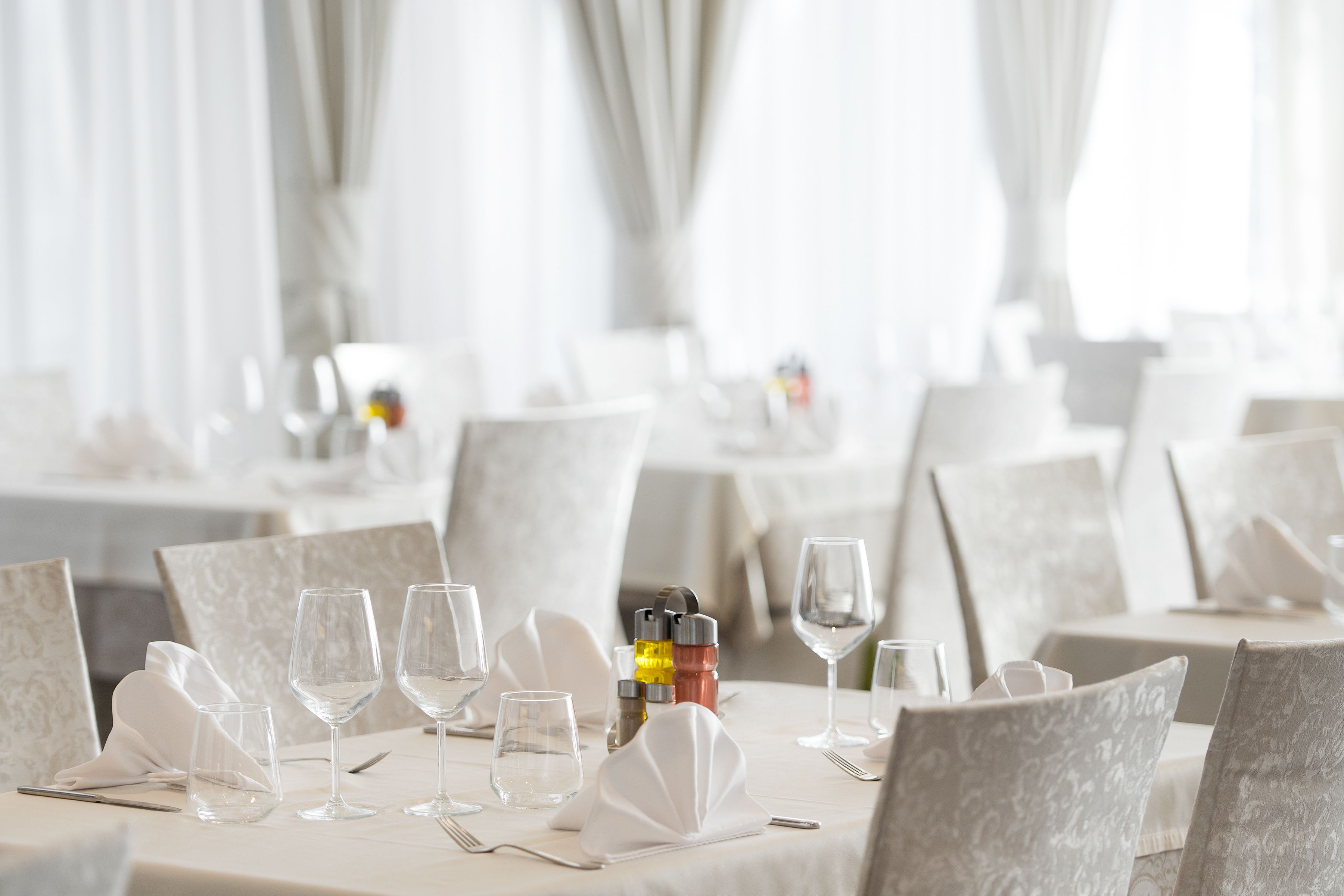 Un espace repas avec des tables dressées pour le service, agrémenté de nappes blanches et de chaises assorties.