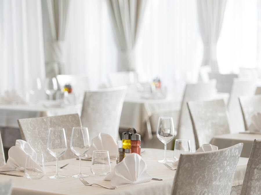 Un espace repas avec des tables dressées pour le service, agrémenté de nappes blanches et de chaises assorties.