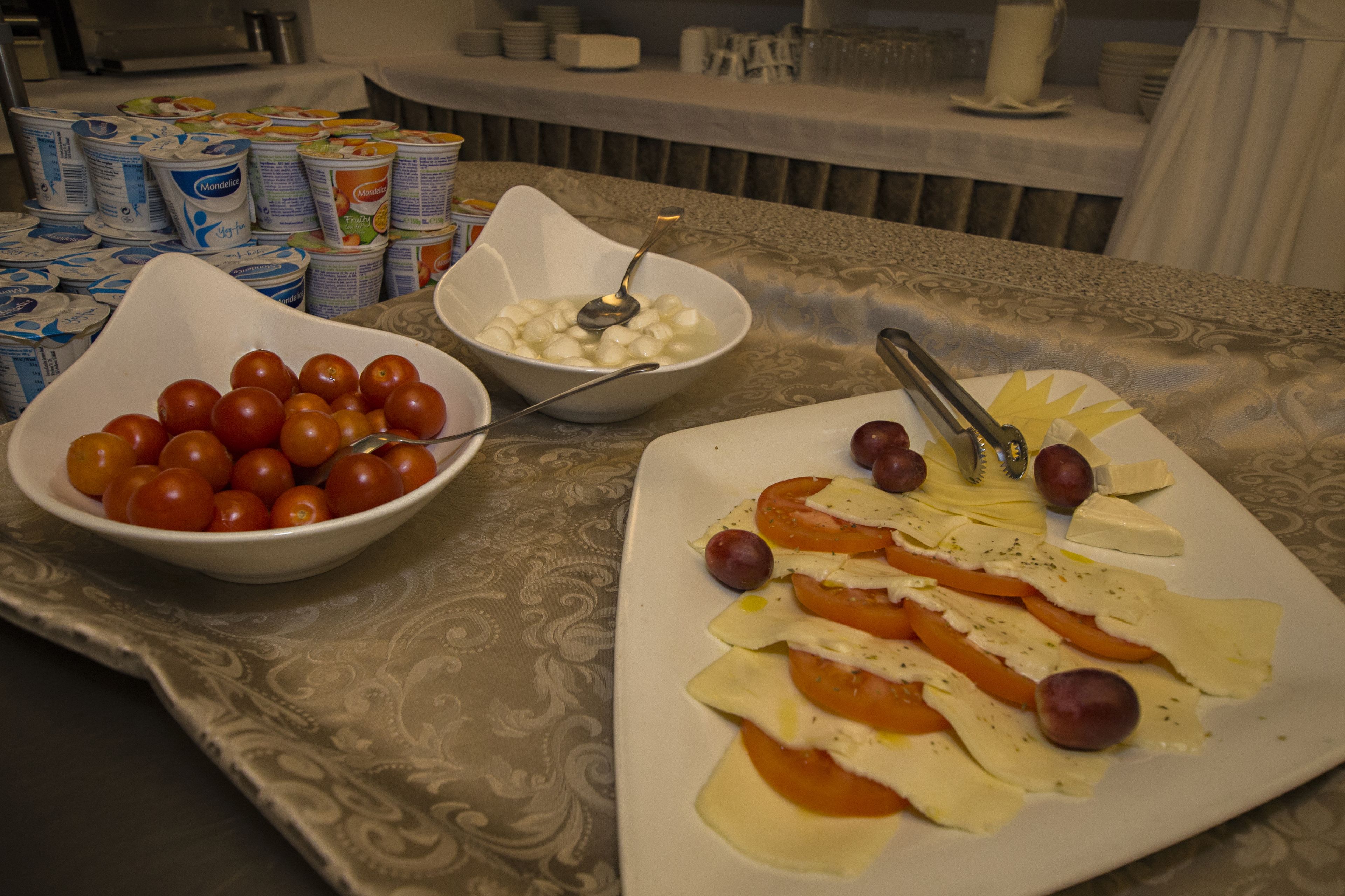 Una mesa con diversos alimentos, como tomates, queso y aceitunas.